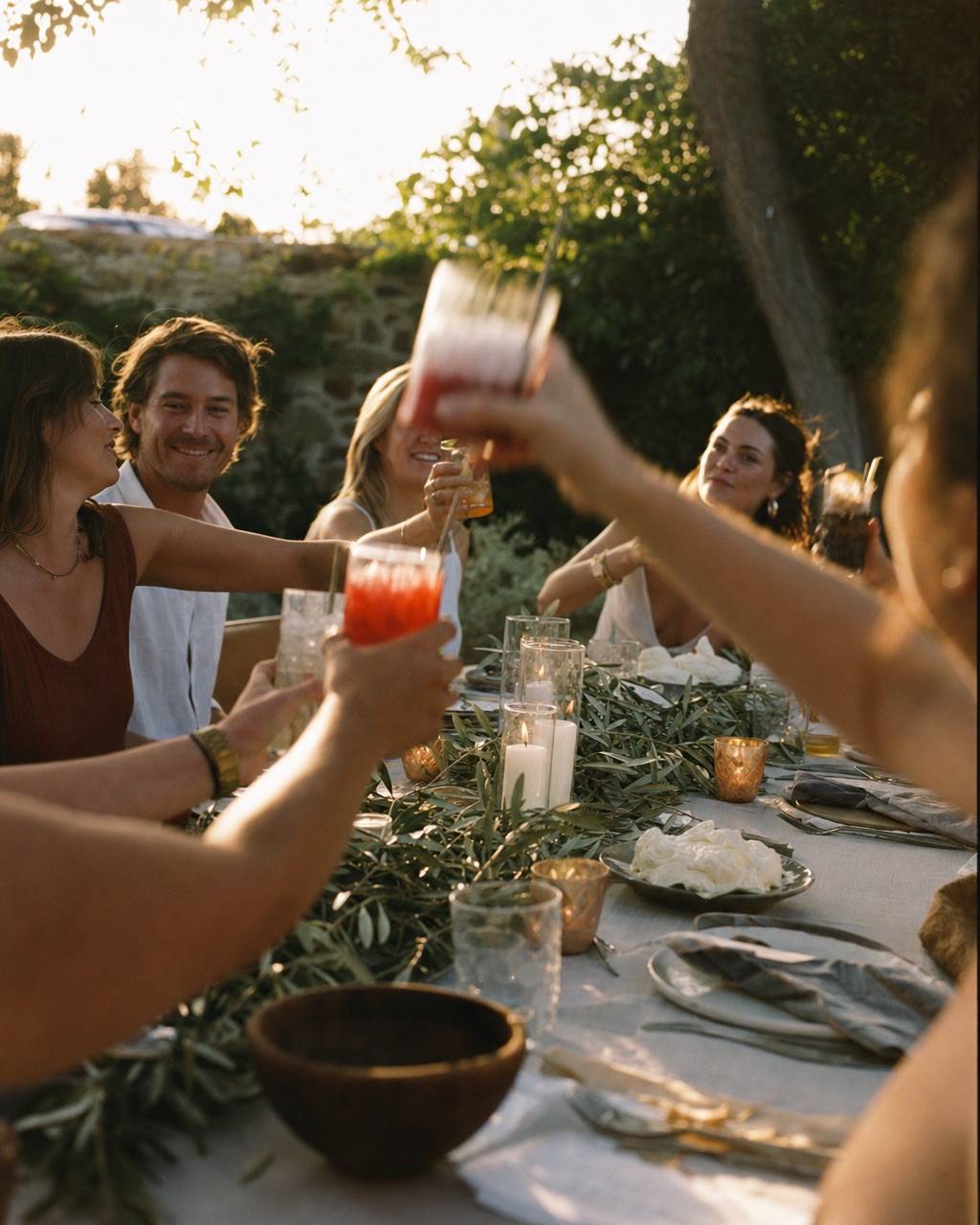 Friends raising glasses at a long outdoor table at golden hour